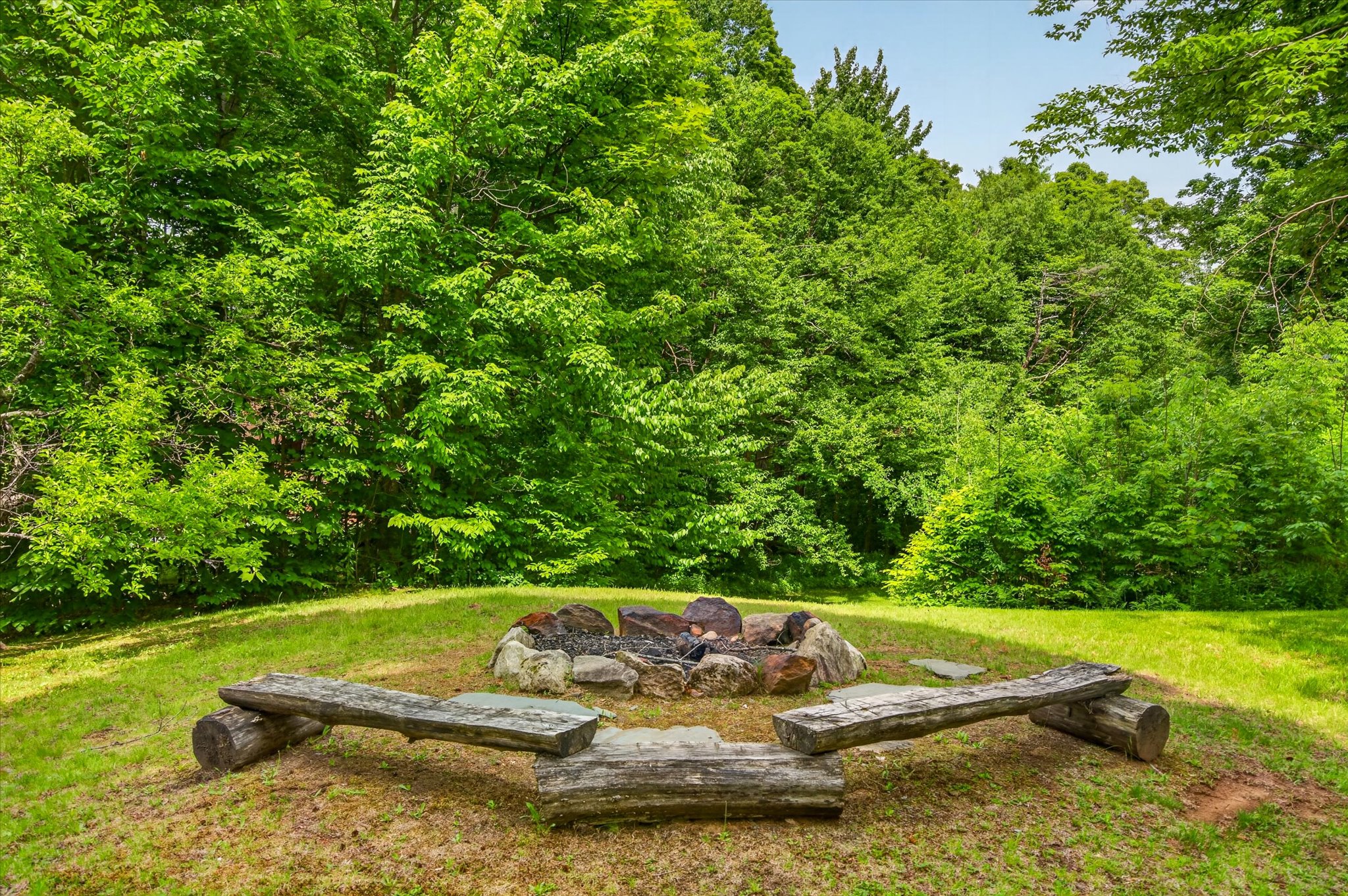 Fire pit with log benches surrounded by Vermont forest — Slippery Slope Chalet