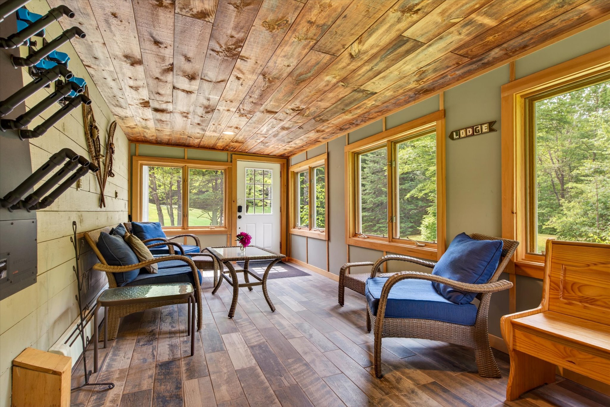 Sunroom with wicker furniture and Vermont forest views — Slippery Slope Chalet